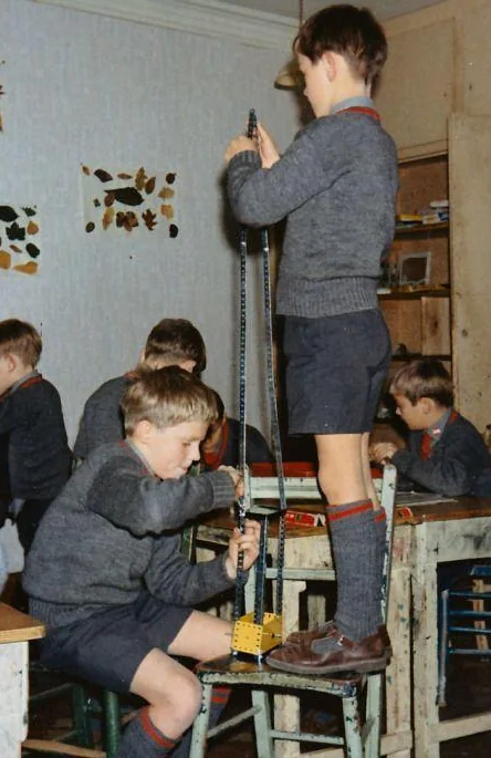 Schoolboys building a tall Meccano tower in a classroom